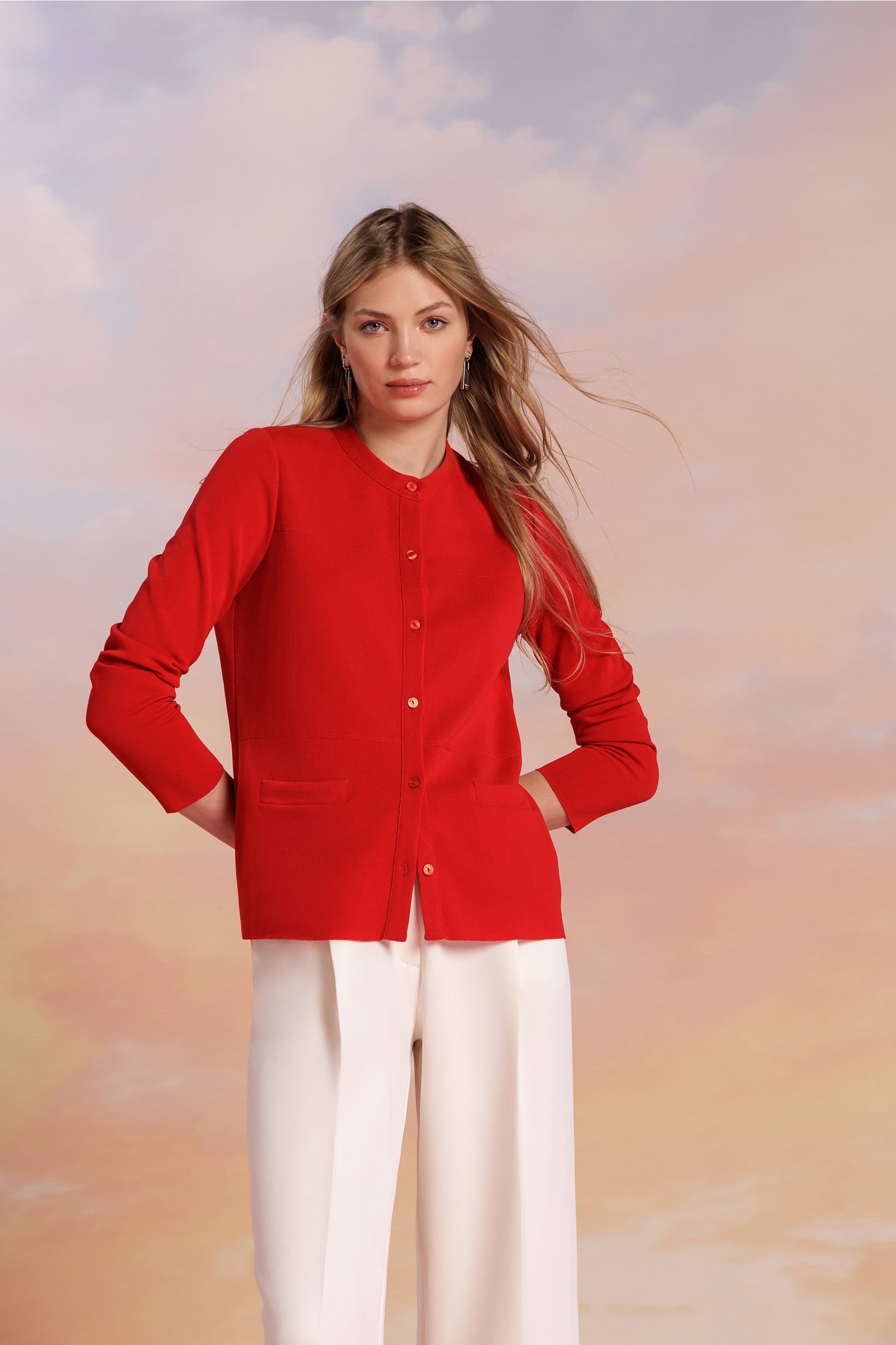 Mujer con una chaqueta roja y unos pantalones fluidos con pinzas de color blanco